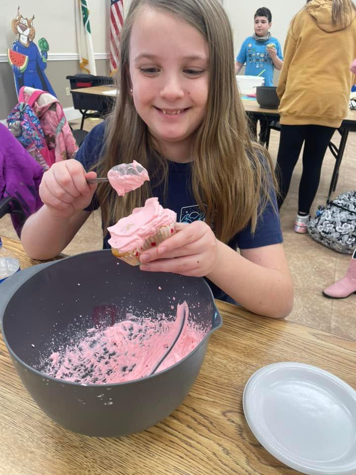 Girl at cooking club icing cupcakes